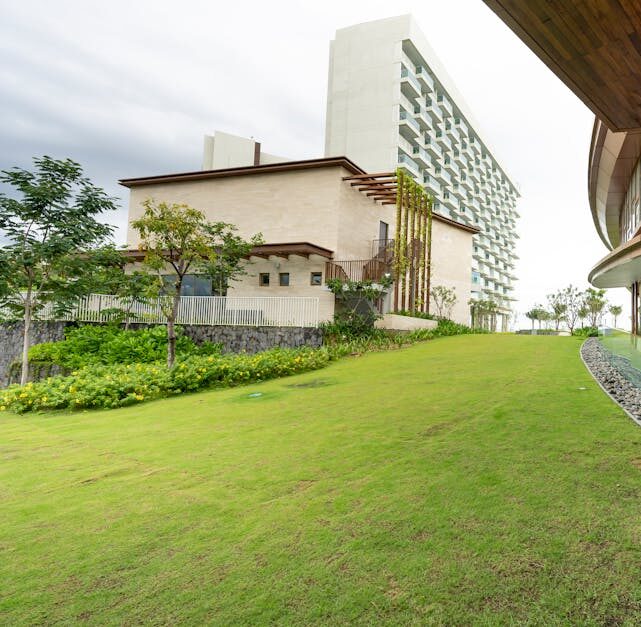 A modern architectural building with lush green surroundings, emphasizing eco-friendly design.
